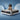 Smiling woman sitting on SpringFit Bonnell Spring Premium Mattress giving a thumbs up against a blue studio background